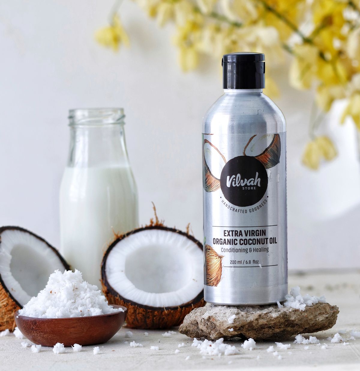 Bottle of organic coconut oil surrounded by fresh coconuts