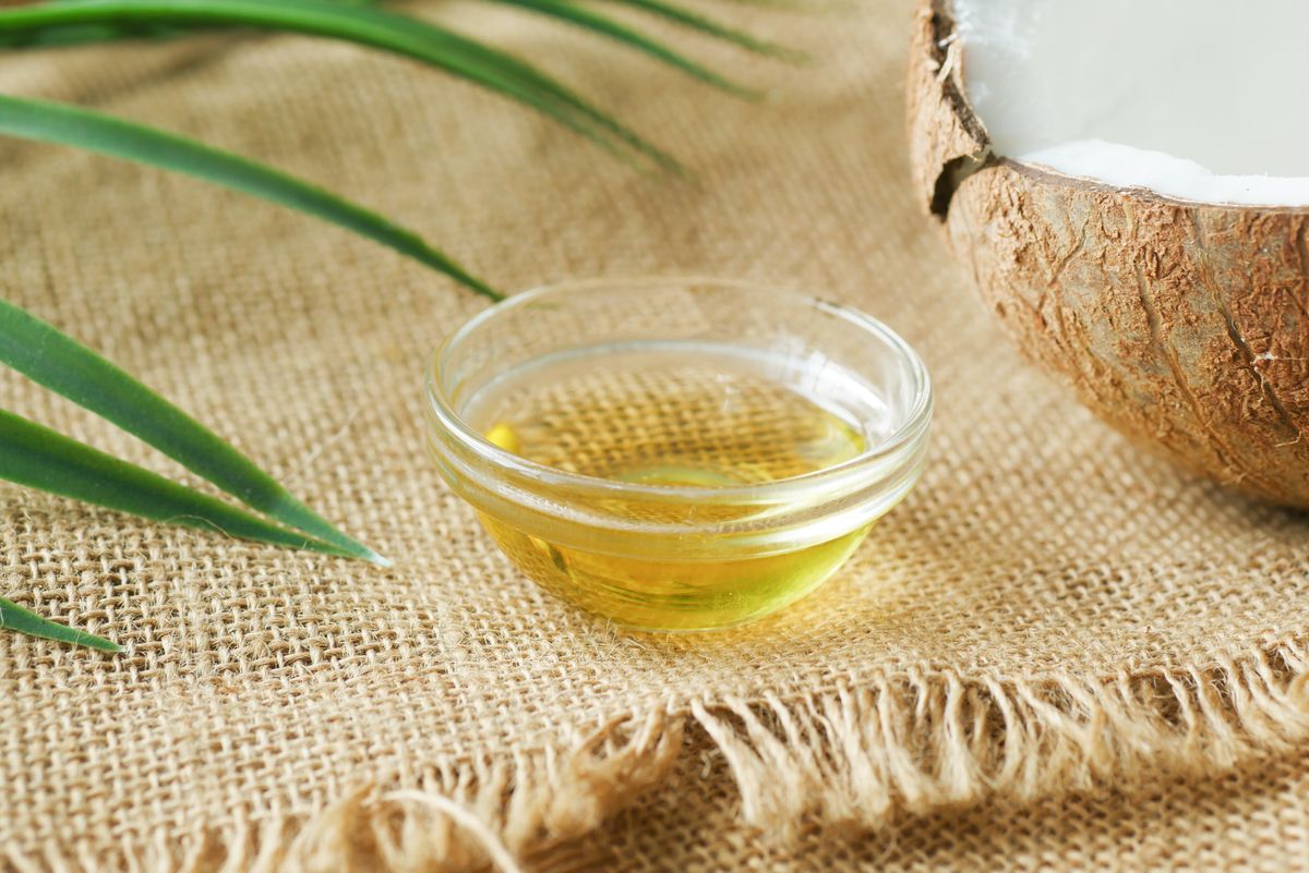 Coconut oil in a glass bowl on burlap with coconut shell