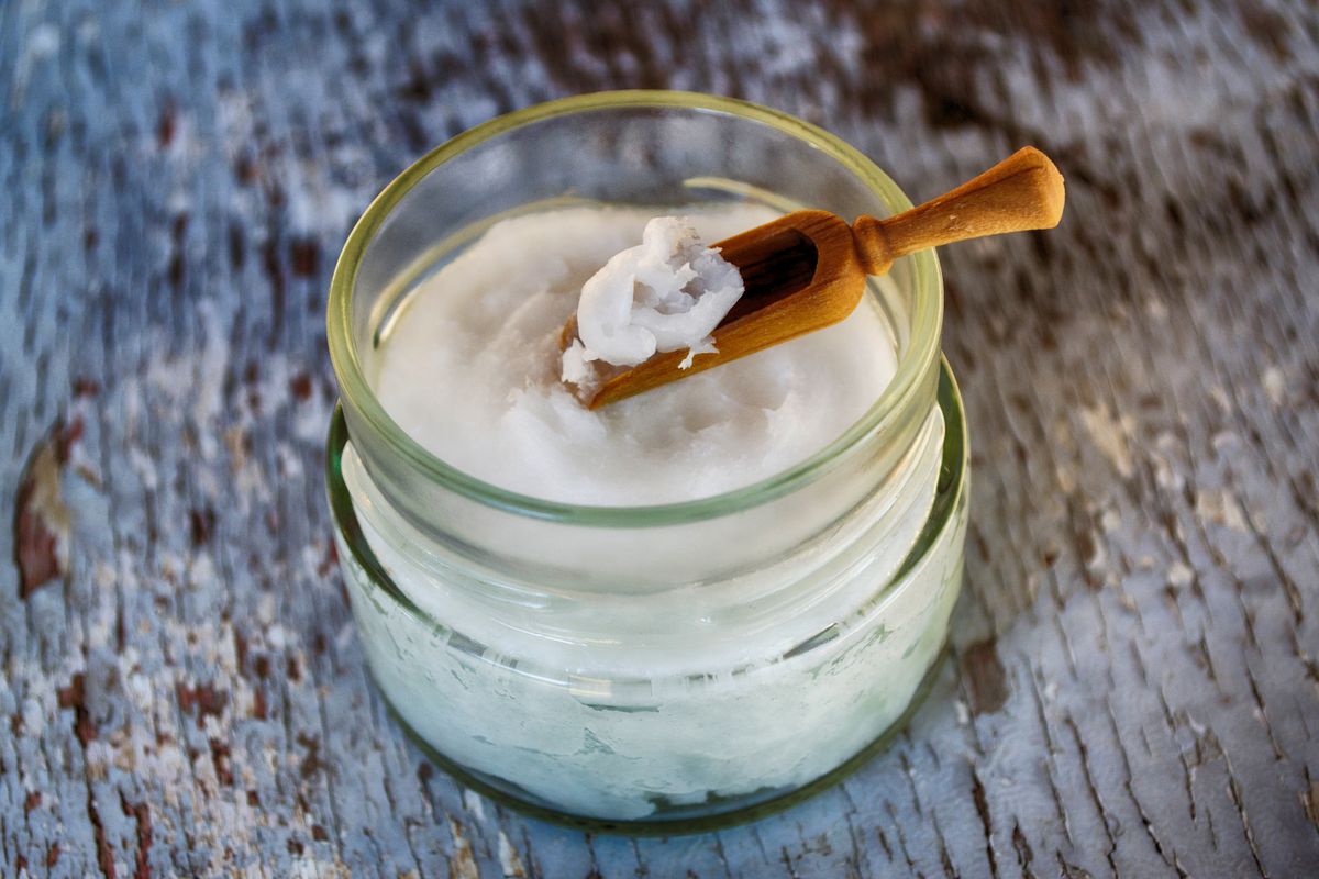 Organic coconut oil in a glass jar with a wooden spoon