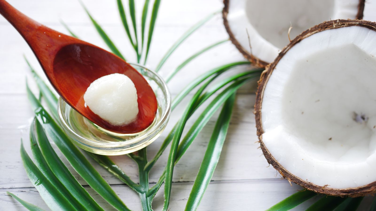 A jar of coconut oil and a wooden spoon, used for oil pulling to support oral health