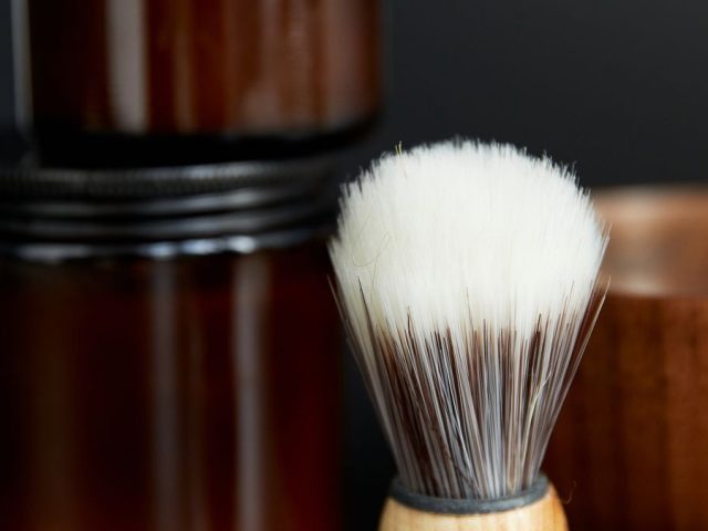 A jar of homemade whipped coconut oil shaving cream with a brush