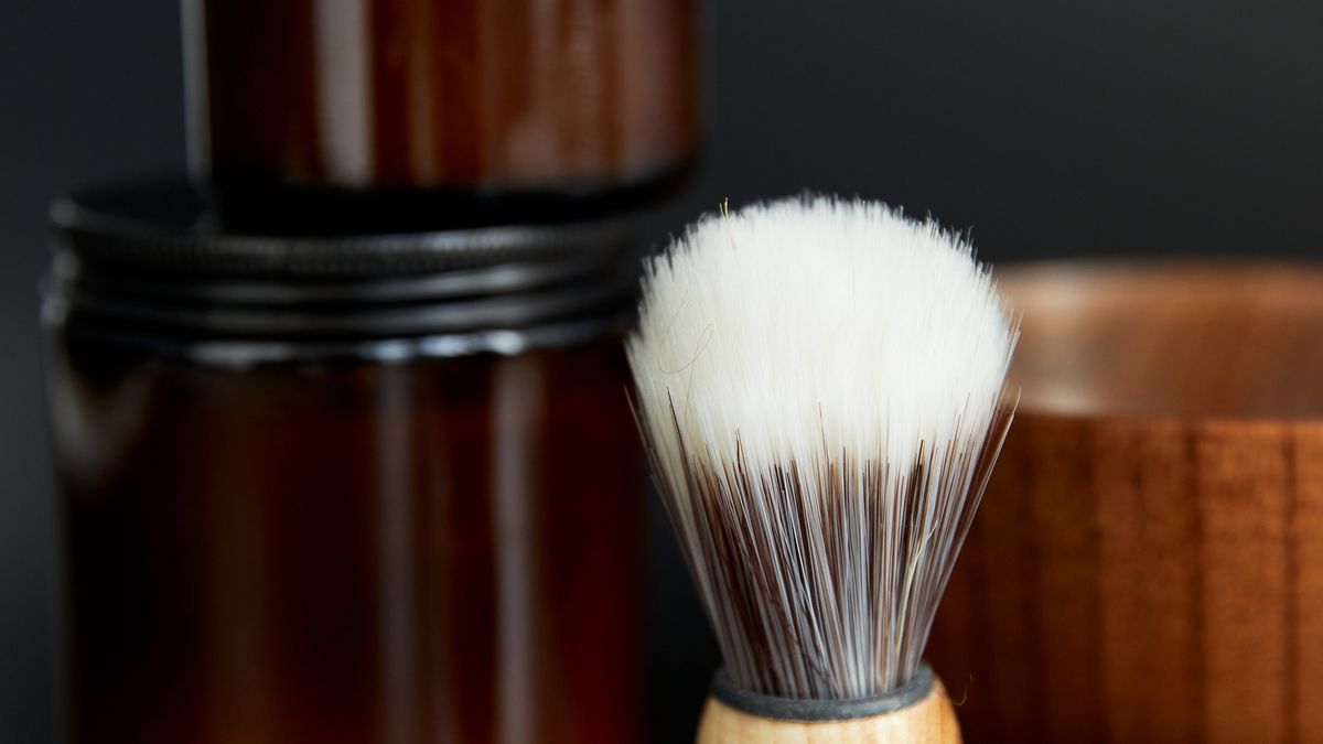 A jar of homemade whipped coconut oil shaving cream with a brush
